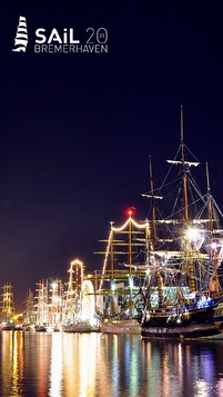 Beleuchtete Segelschiffe stehen im Neuen Hafen links und rechts entlang des Hafenbeckens.